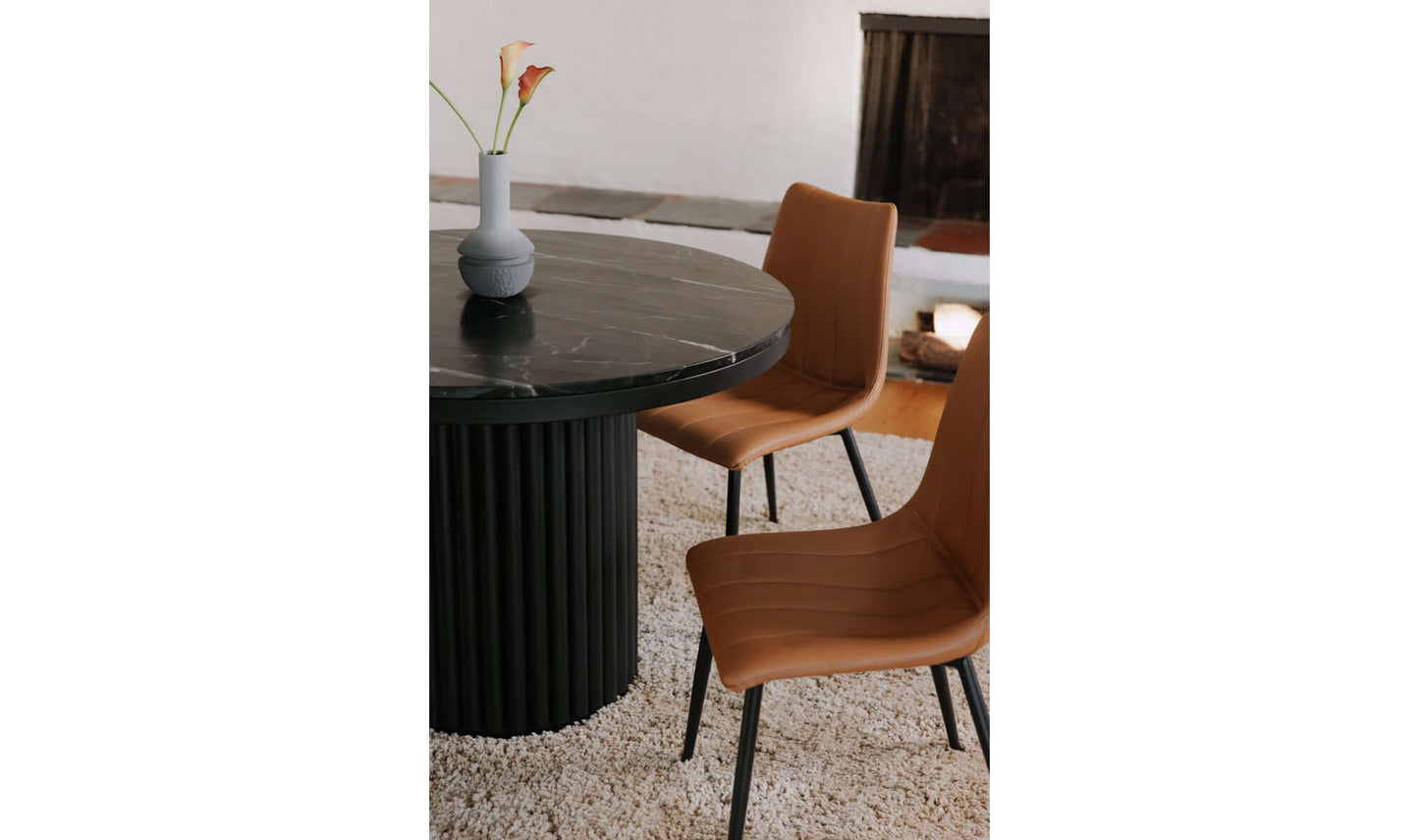Close-up of the Tower Black Marble Dining Table by Moe’s Home Collection with two tan chairs, showcasing its luxurious marble top and elegant pillar base.