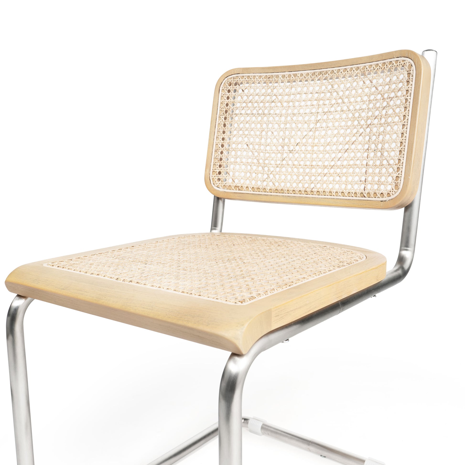 Angled close-up of silver cane dining chair showcasing its woven cane seat and steel structure.