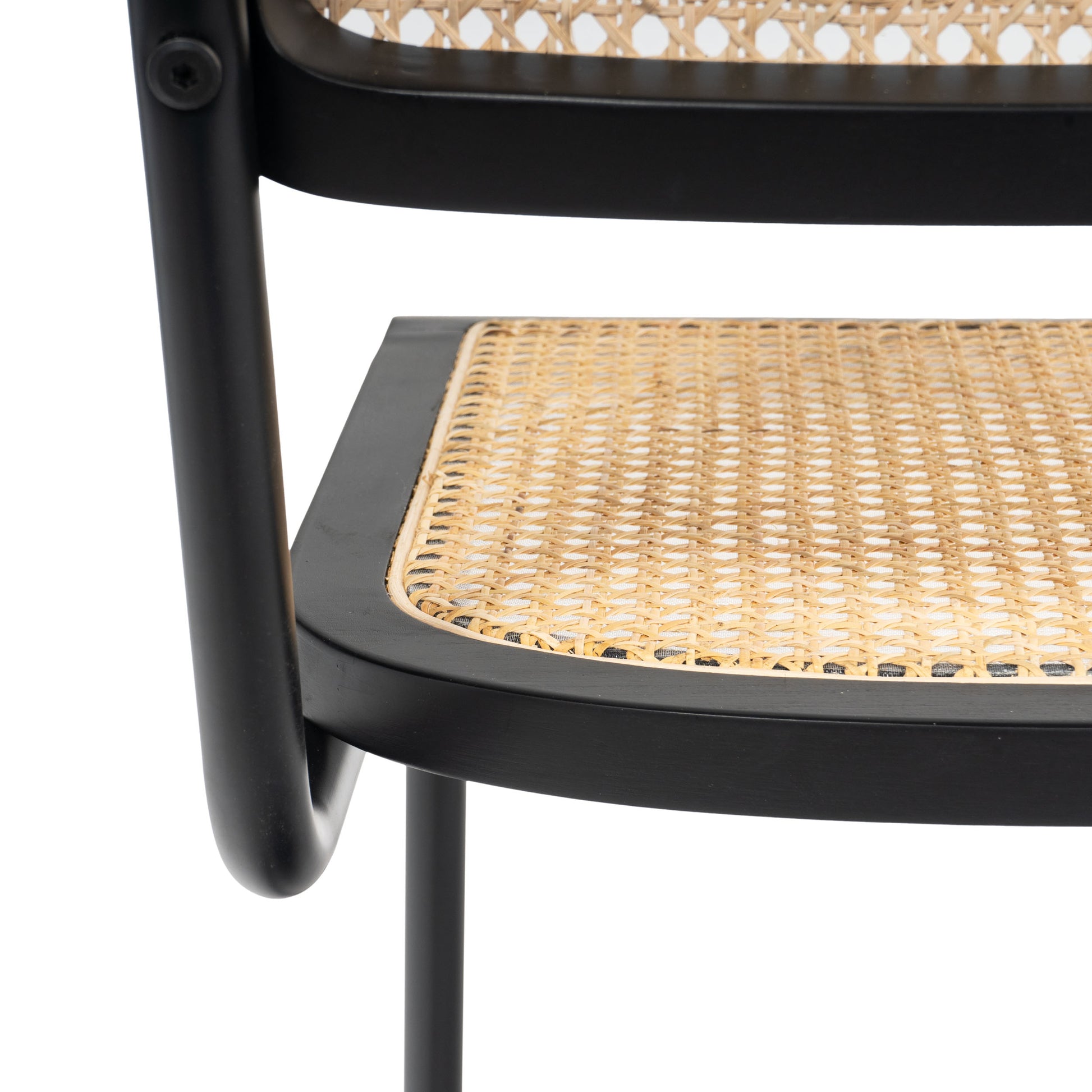 Close-up of the woven rattan seat on a black cane dining chair, highlighting the intricate weave.