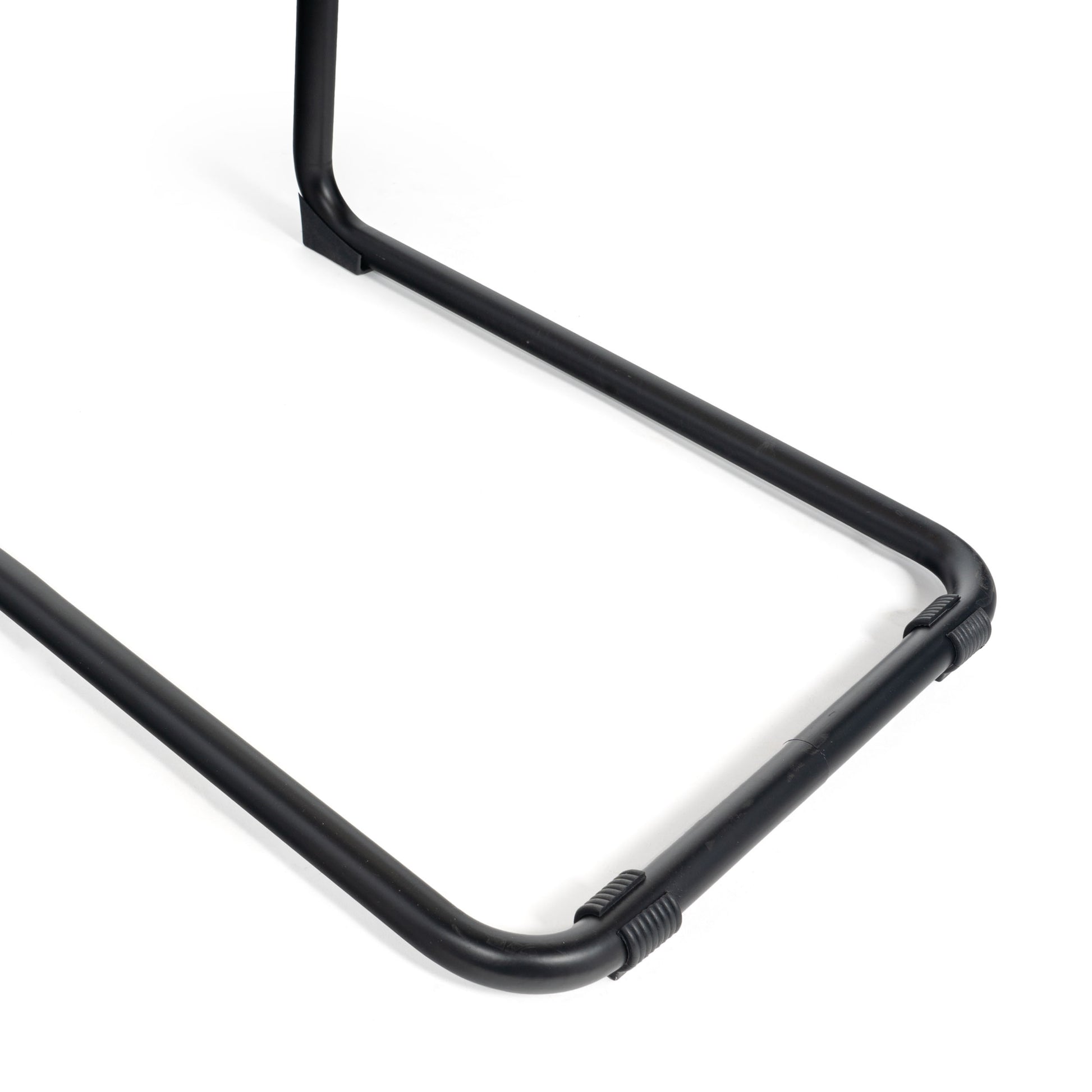 Detailed view of the tubular steel base of a black cane dining chair, featuring anti-slip pads for stability.