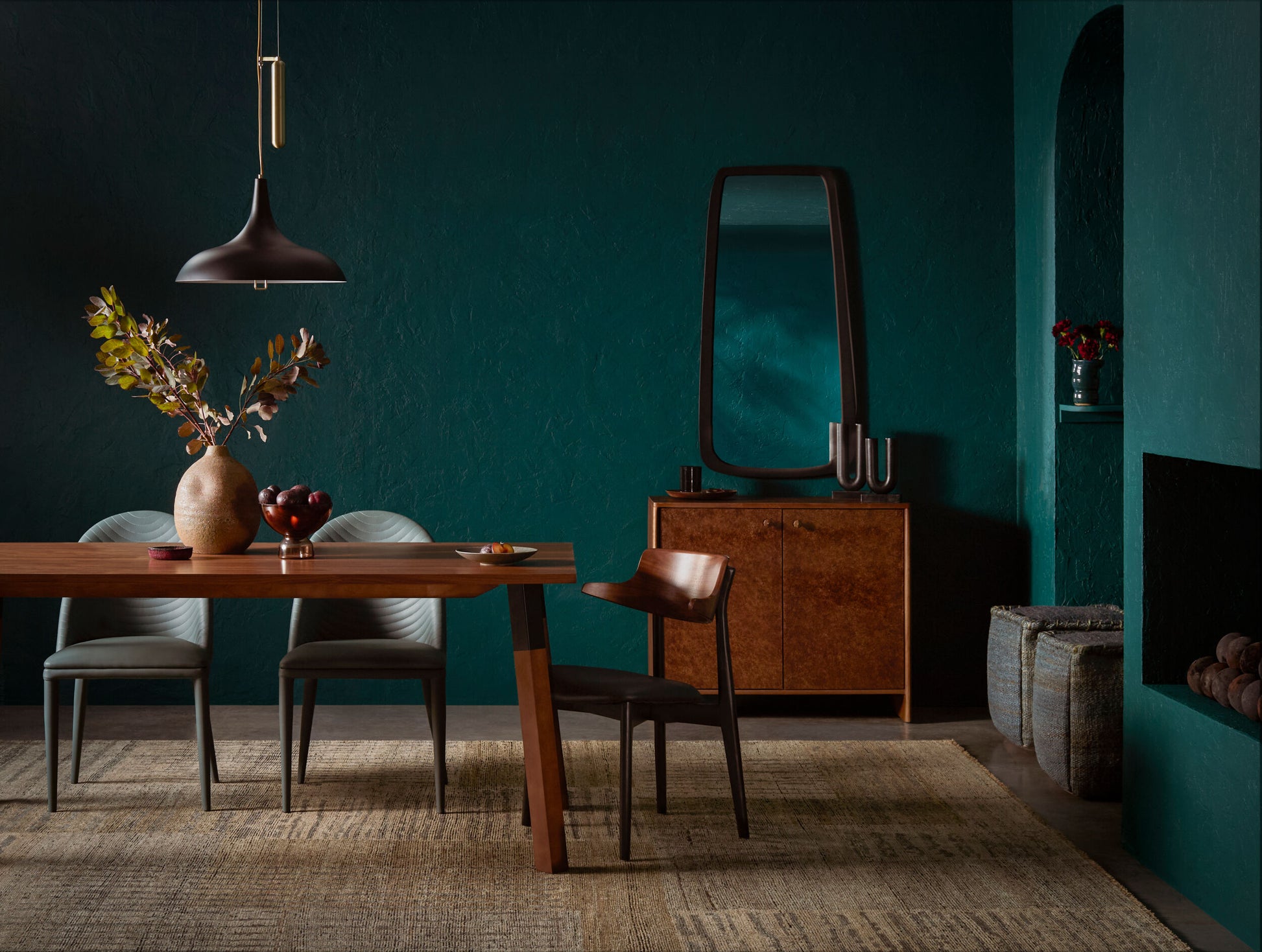 Black oak dining chair with brown faux leather seat at a modern wood table in a moody green dining room.