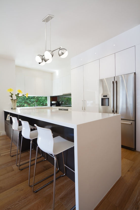 Brushed nickel chandelier above white kitchen island.