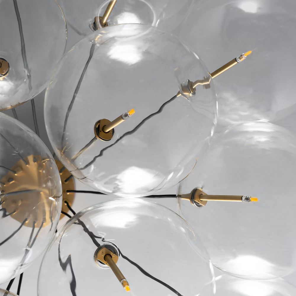 Close-up of clear glass globes with brass accents and LED bulbs on the cluster chandelier.