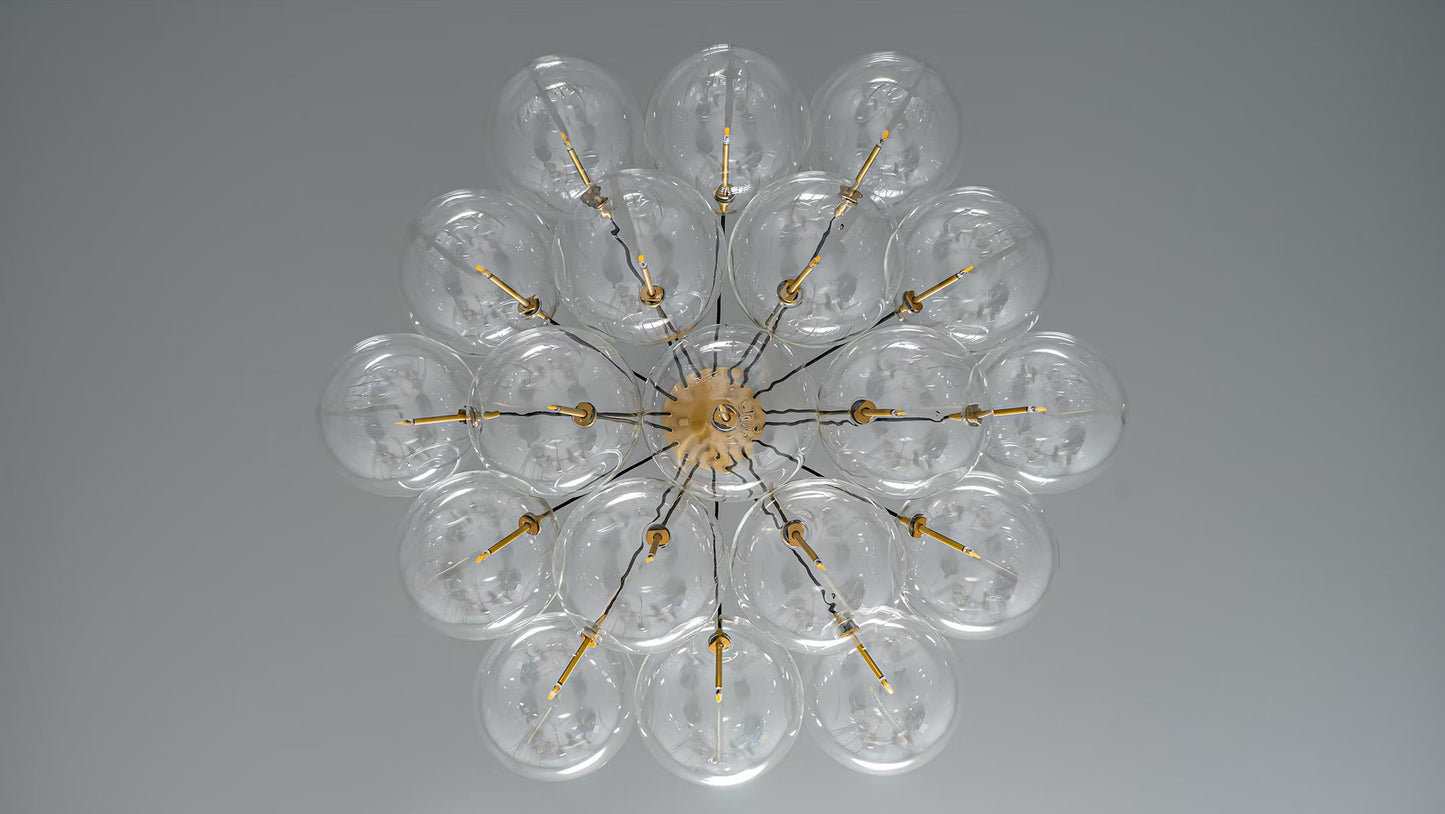 A bottom view of a cluster chandelier with clear glass globes, brass hub, and black cords.