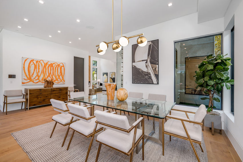 modern gold chandelier above glass dining table.