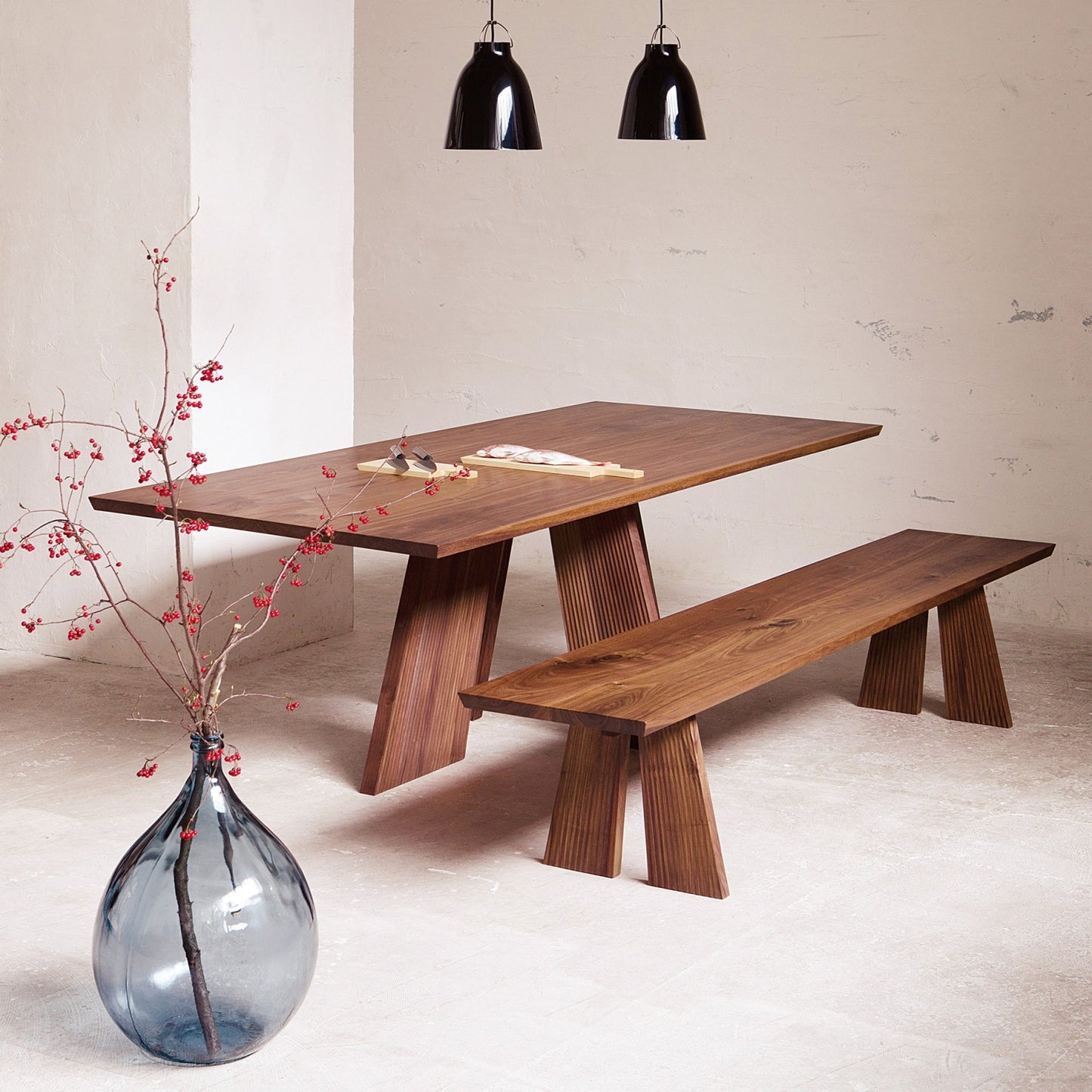 Hakama Dining Table with a matching bench, showcasing its sculptural legs.