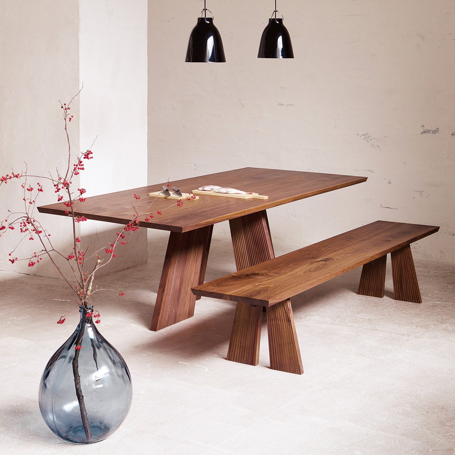 Hakama Dining Table with a matching bench, showcasing its sculptural legs.