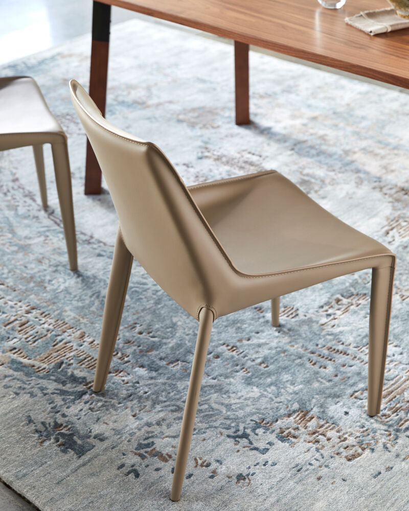 Light brown PVC dining chair with a sleek design, positioned near a wooden table on a blue-patterned rug.