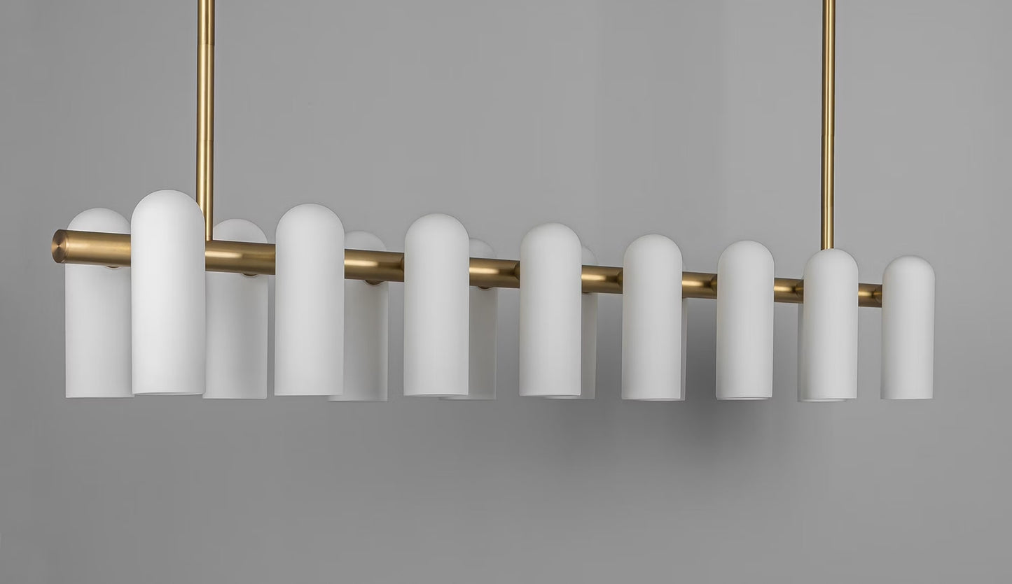 Oversized brass linear chandelier with frosted cylindrical shades in a contemporary style.