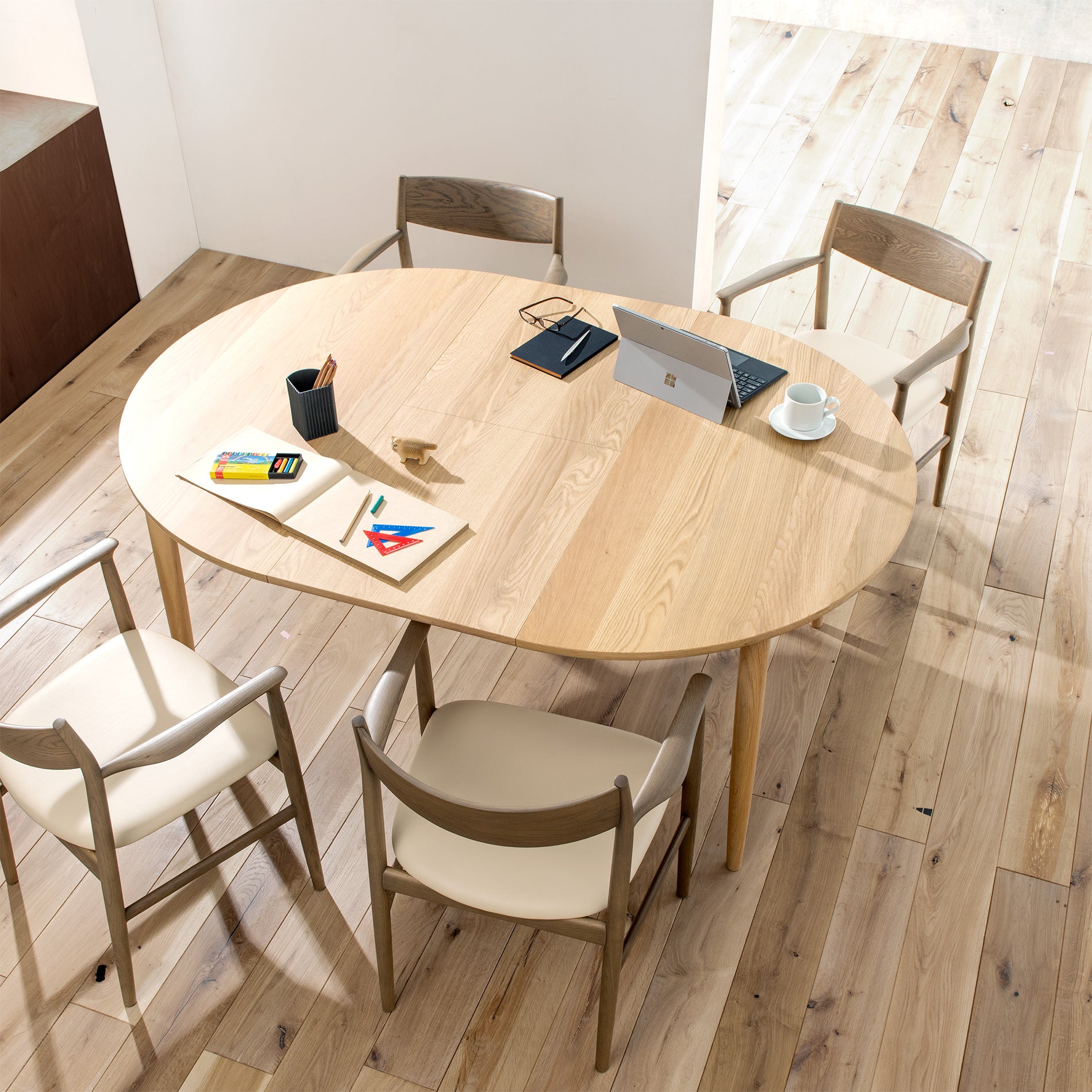Modern round extension dining table set in a bright workspace with natural lighting.