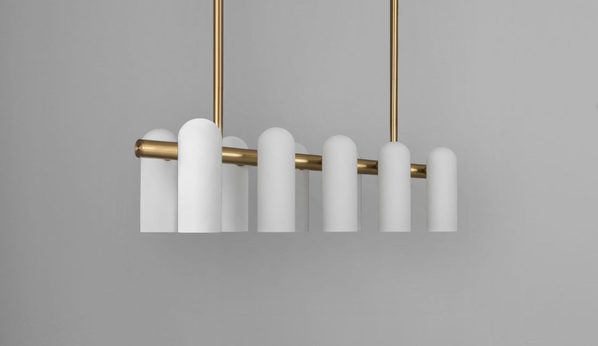 Modern brass linear chandelier featuring frosted glass shades and elegant warm metallic accents.