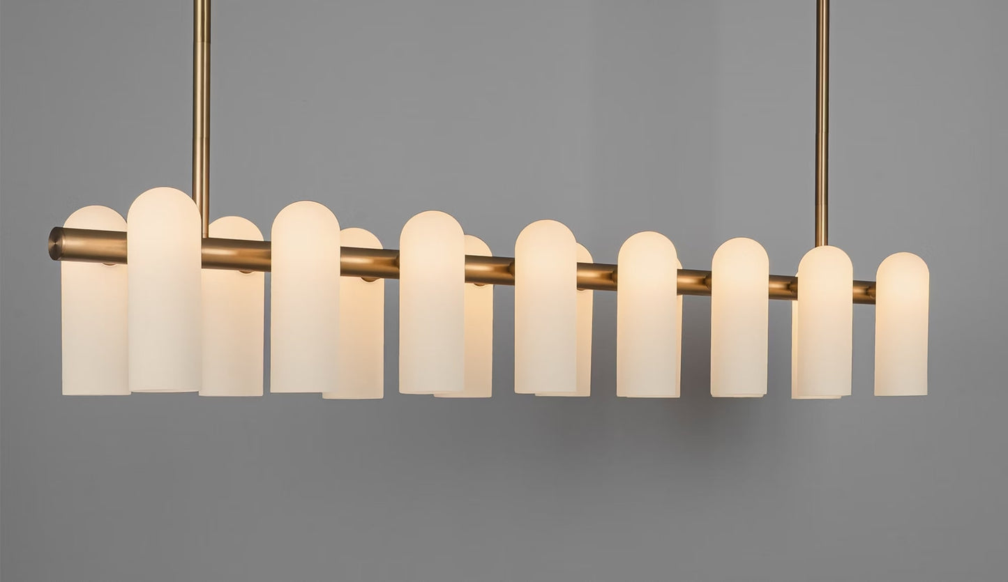 Elegant large chandelier lit with a soft warm glow, highlighting frosted glass shades and brass base.