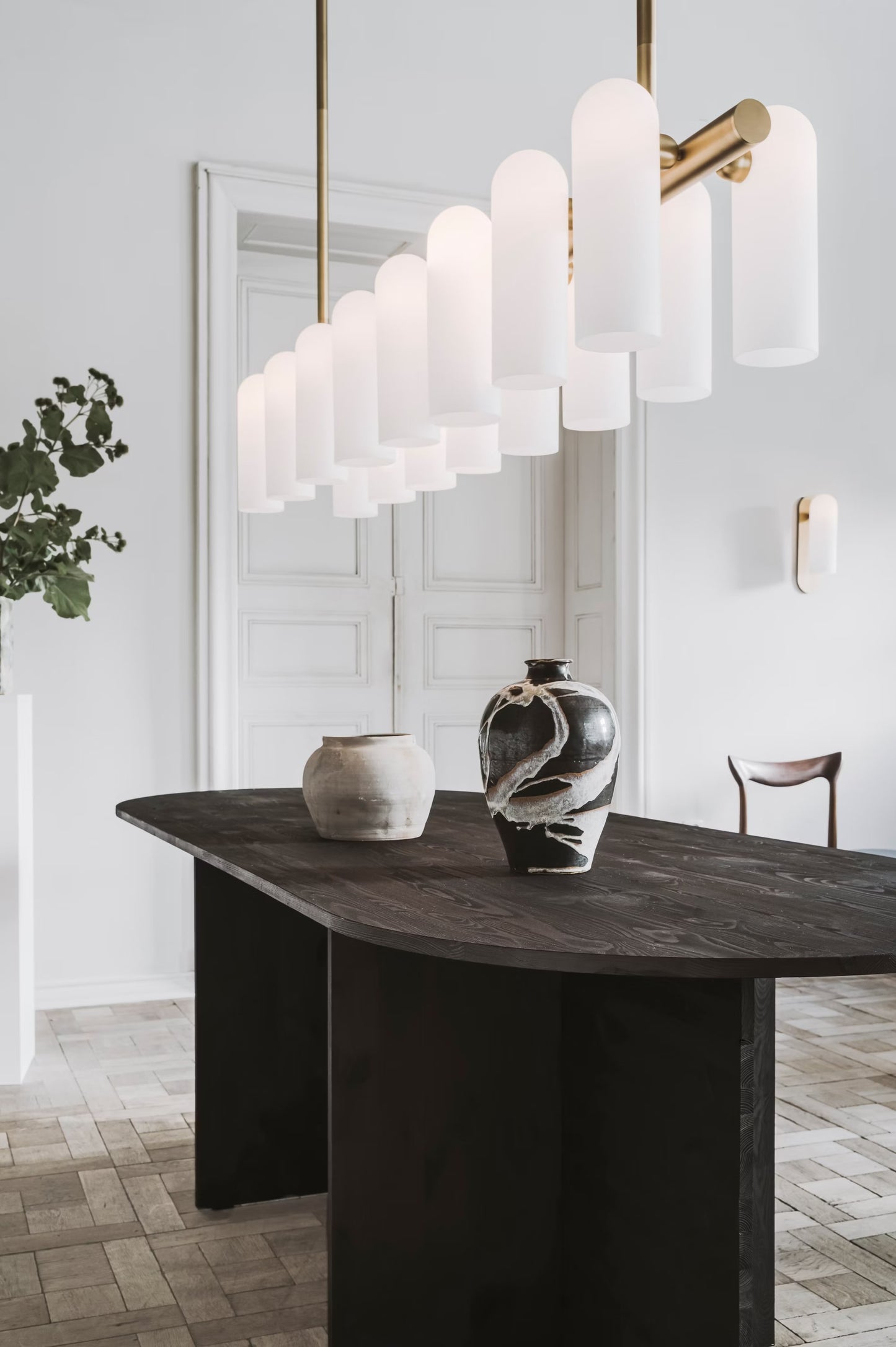 Large brass chandelier with frosted glass shades, featured above a dark wood dining table.