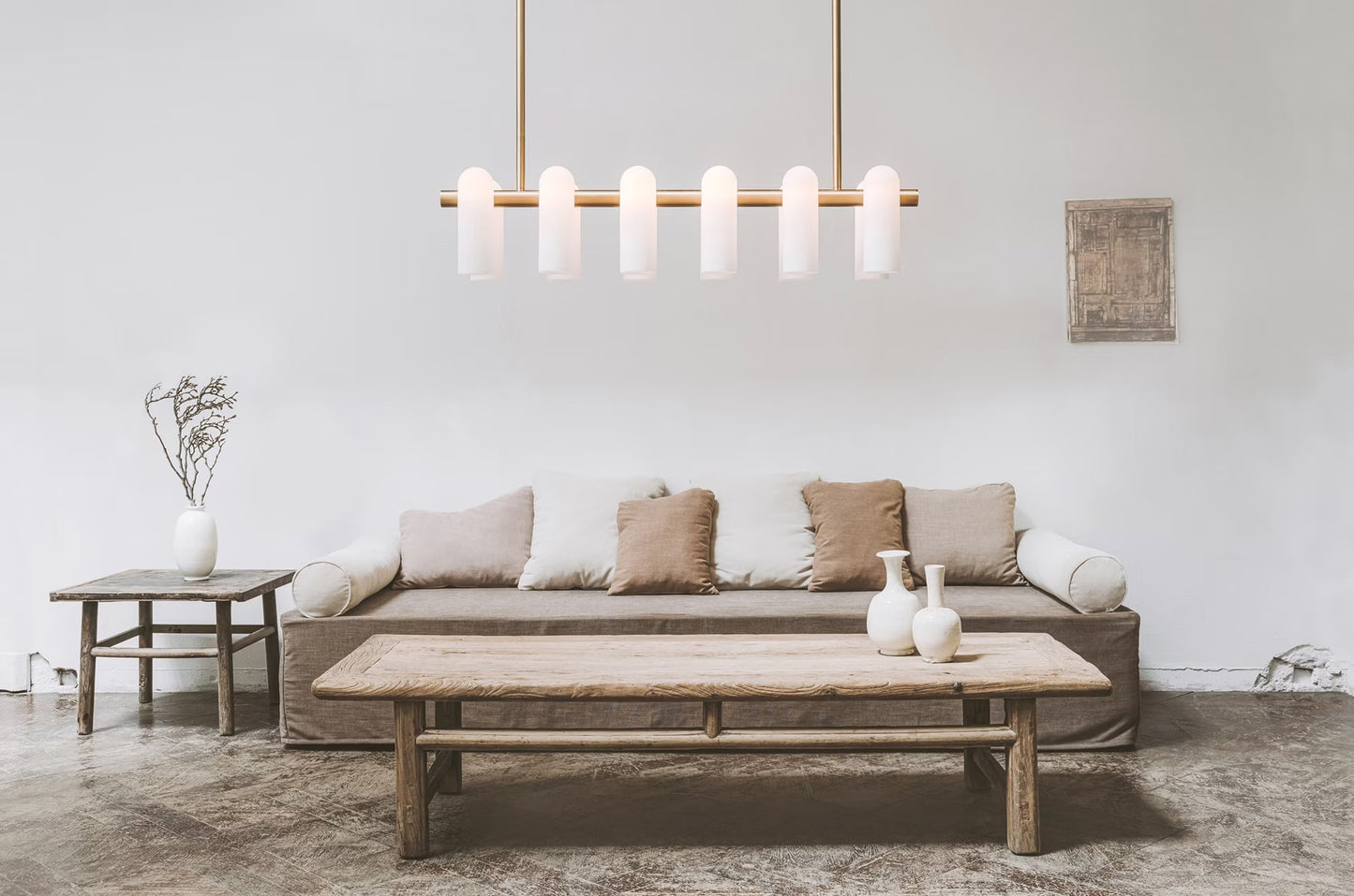 Minimalist chandelier with brass finish and white frosted shades in a modern living room setting.
