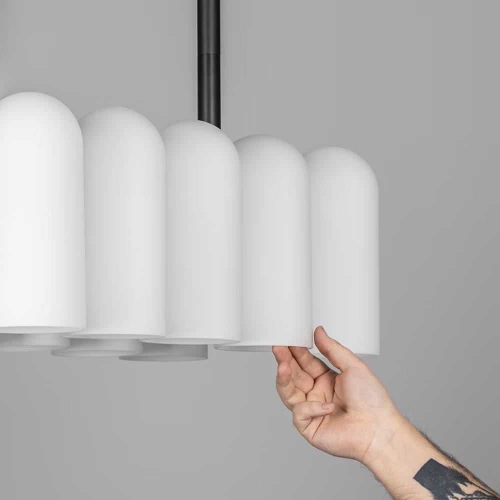 Hand touching a frosted glass shade, showcasing the craftsmanship of the chandelier design.