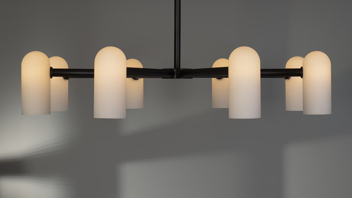 Black gunmetal chandelier with glowing opal glass shades, casting warm ambient light.