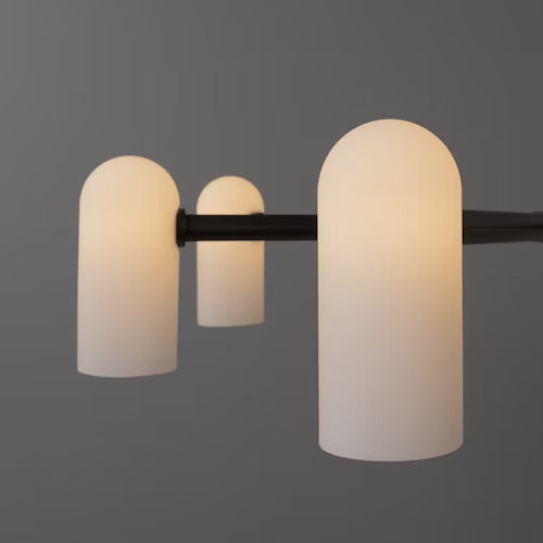 Close-up of a black chandelier with softly glowing opal glass shades in a modern setting.