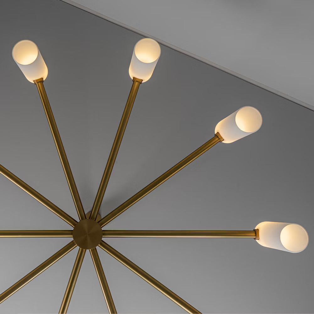 Brass chandelier viewed from below with warmly illuminated cylindrical opal glass shades.