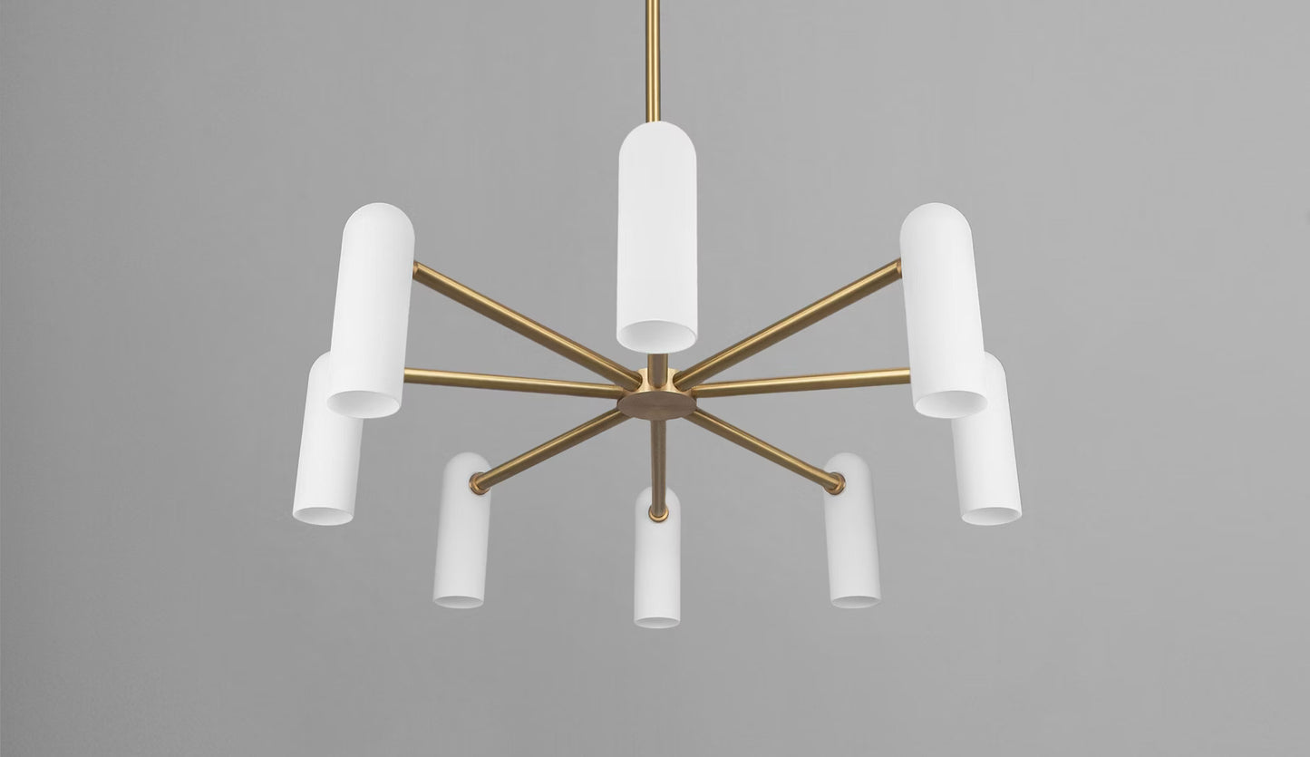 Brass chandelier with eight cylindrical white opal glass shades against a soft gray background.