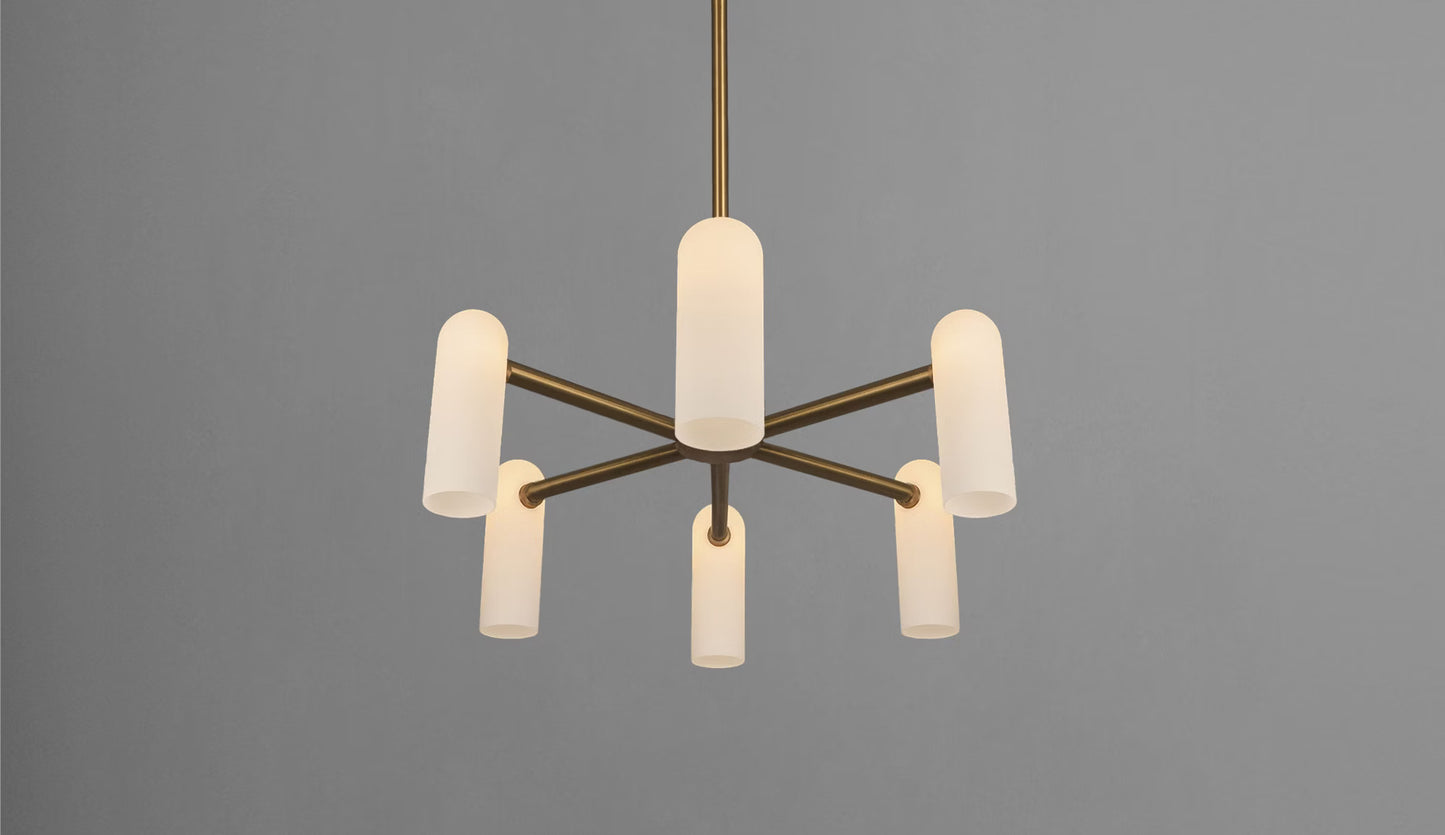 Brass chandelier with six glowing opal glass shades, suspended in a minimalist interior.