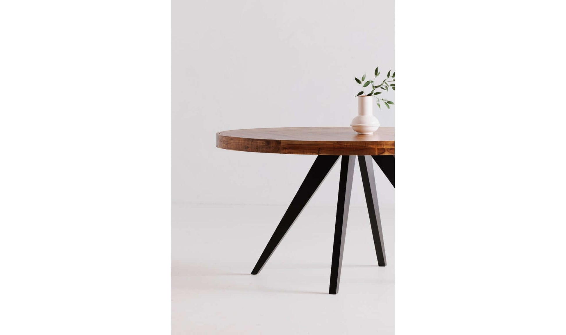 Minimalist setup of the Parq Oval Rustic Dining Table with a white vase on a plain background