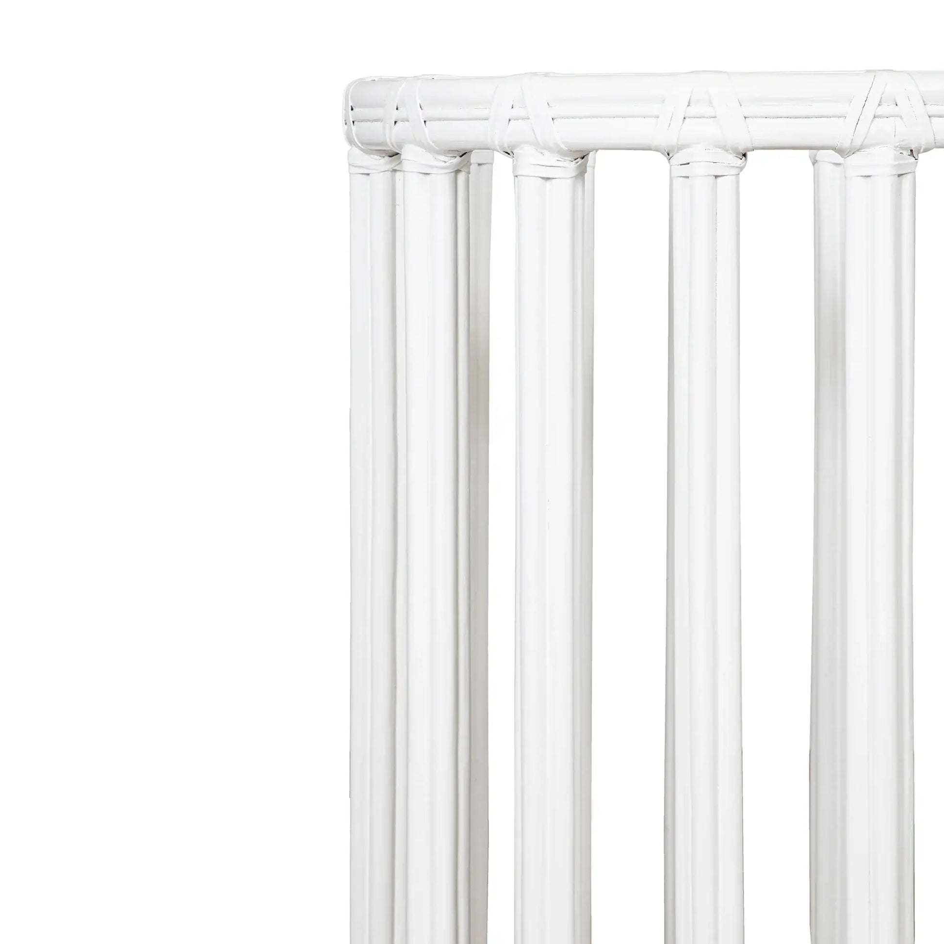 Edge detail of a white round metal table base with rattan design.