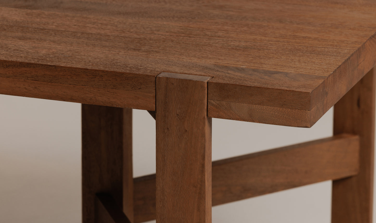 Corner view of the Workshop wooden dining table for 10, showcasing the smooth finish of the solid mango.