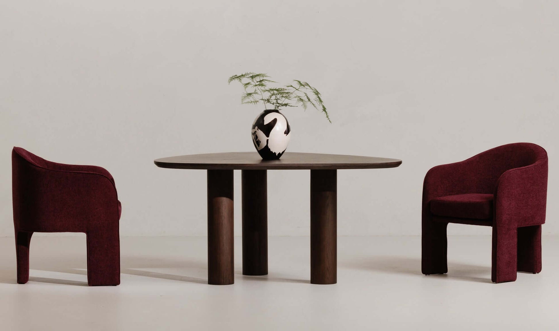 Finley brown contemporary dining table setup in a modern dining room with two burgundy chairs and decorative vase.