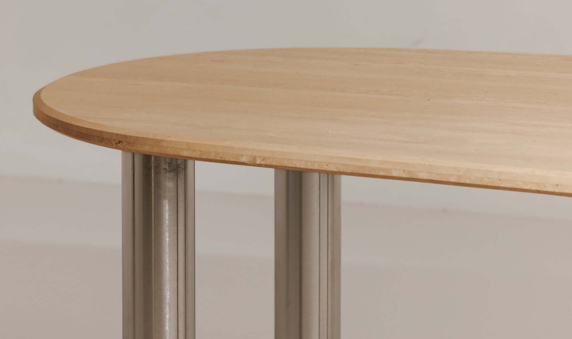 Close-up of the Fia Dining Table Travertine showing the polished chrome legs and Italian travertine top.