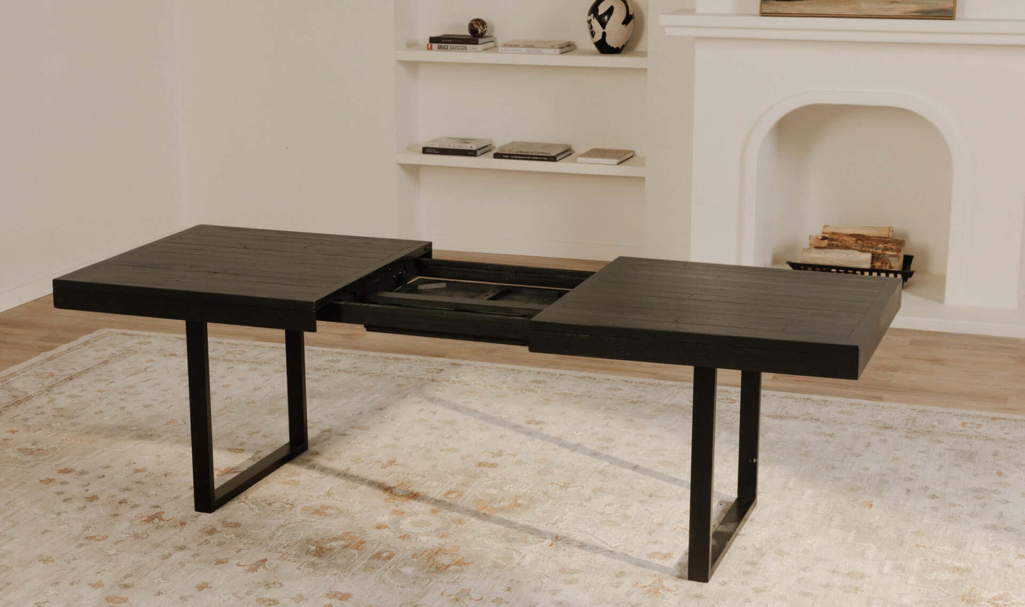 The Ben Extension Dining Table in black, partially extended, with a focus on the innovative self-storage butterfly extension mechanism.