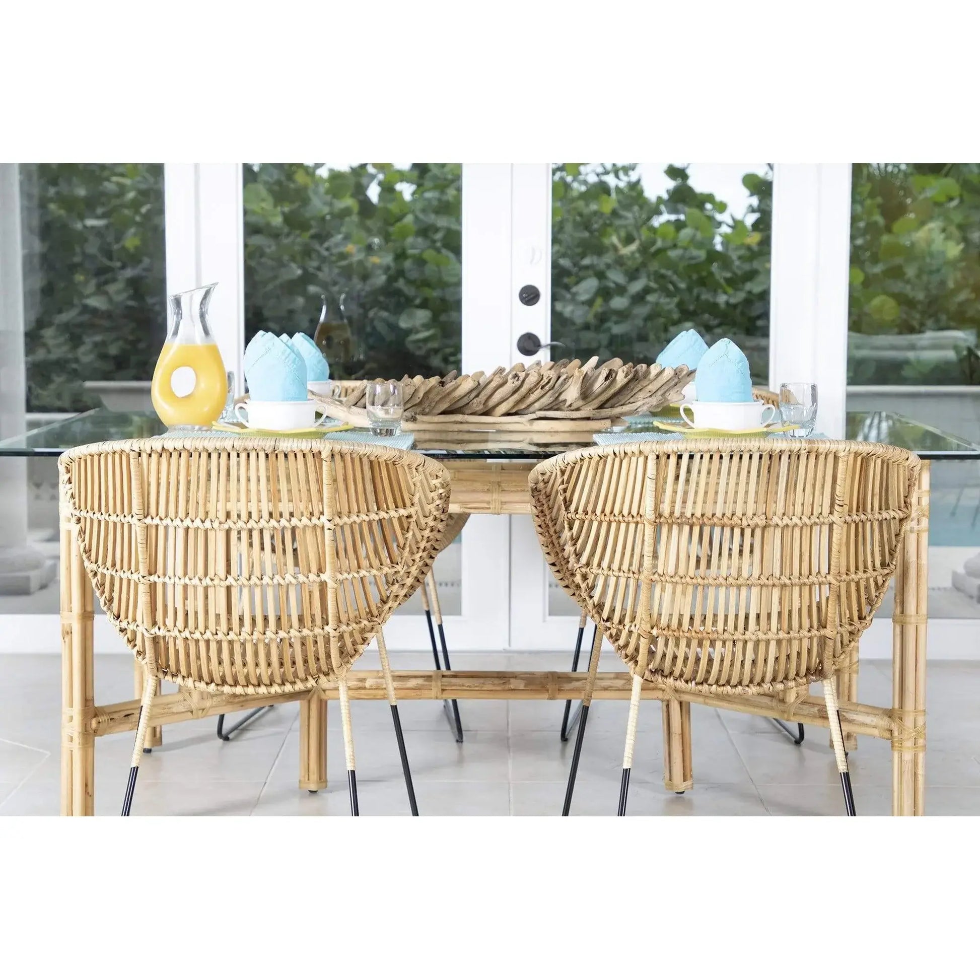 Set of two David Francis Bali modern rattan dining arm chairs with natural rattan, placed in a bright dining space with a glass table.