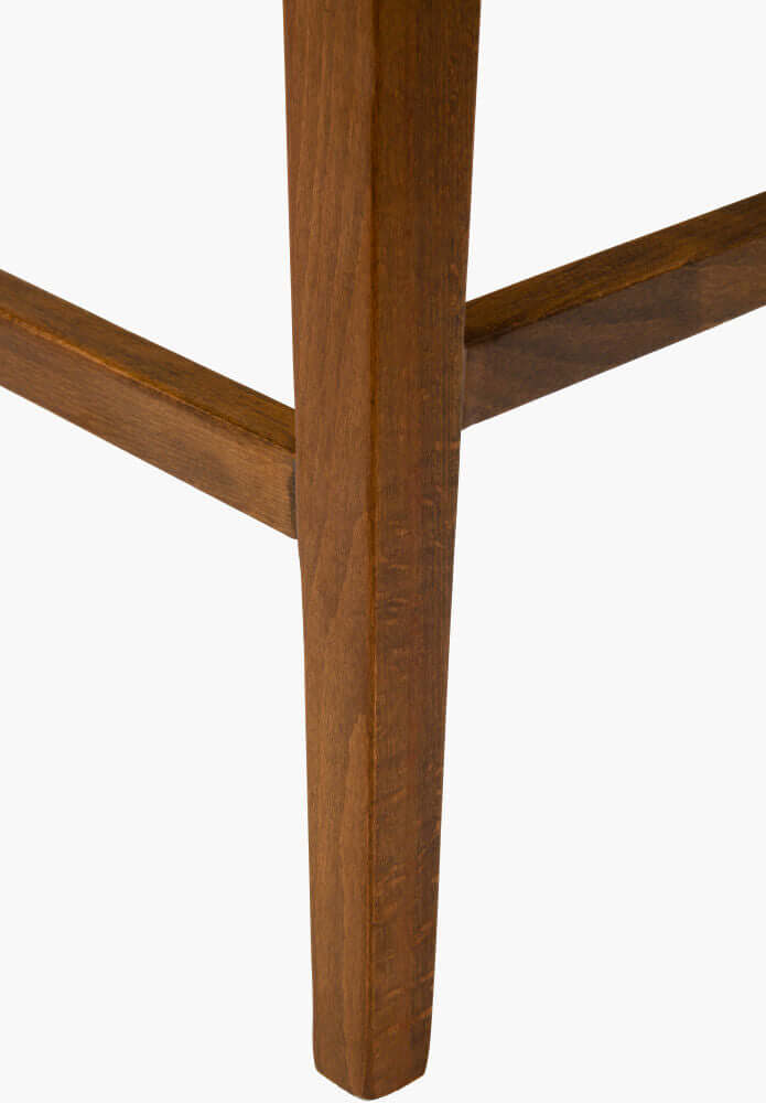 Close-up of Surya Brooke Counter Stool leg in wheat finish beechwood.