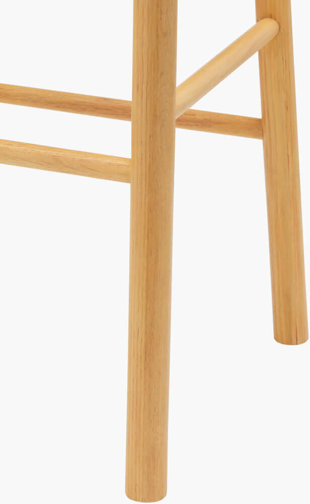 Close-up of Callum bar stool's sturdy oak legs and natural finish.