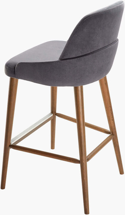 Back angled view of a modern counter stool featuring a dark gray upholstered seat with a curved backrest and wooden legs