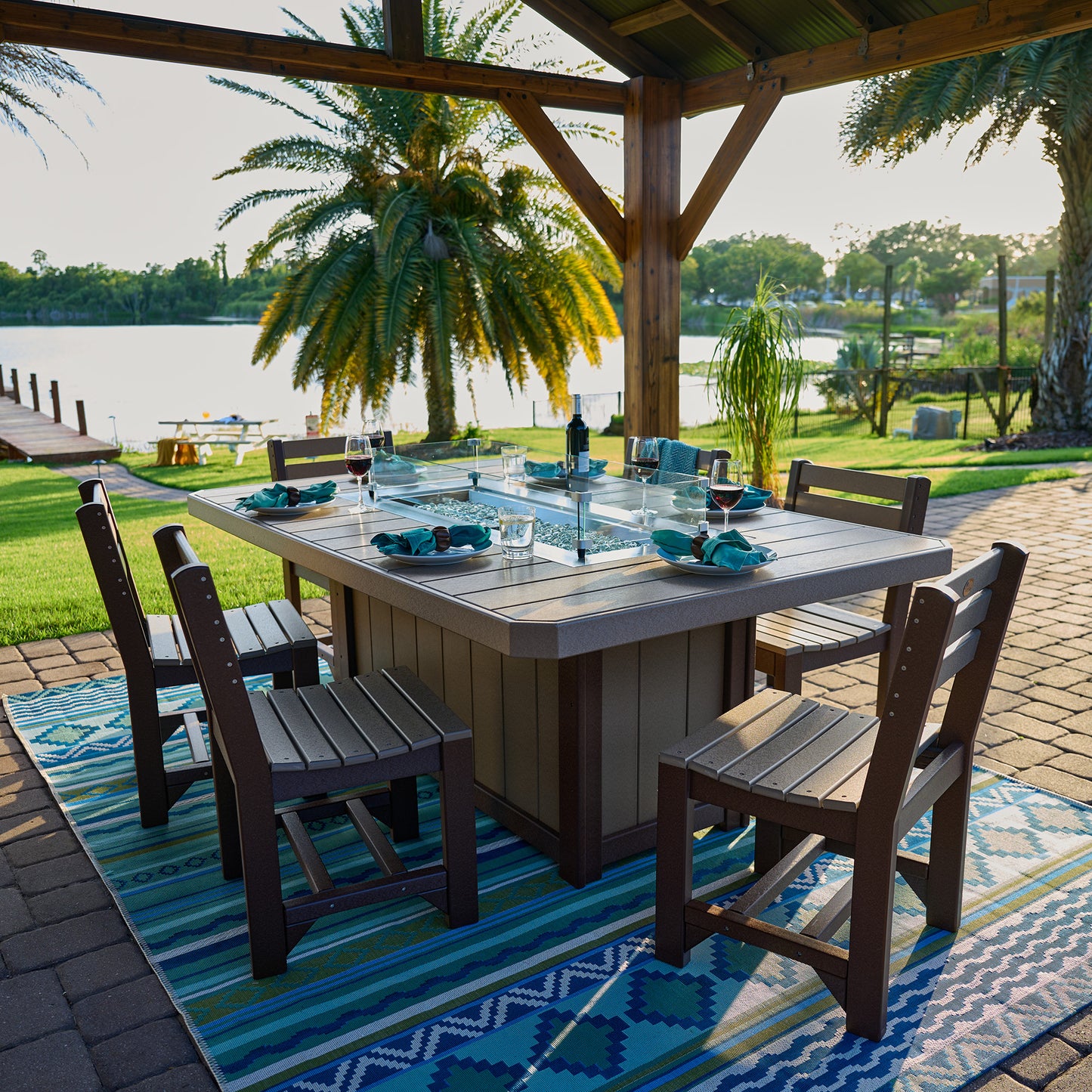 Outdoor Lumin Bar Fire Table 79" in dining setup overlooking serene lake, flame control for ambiance.