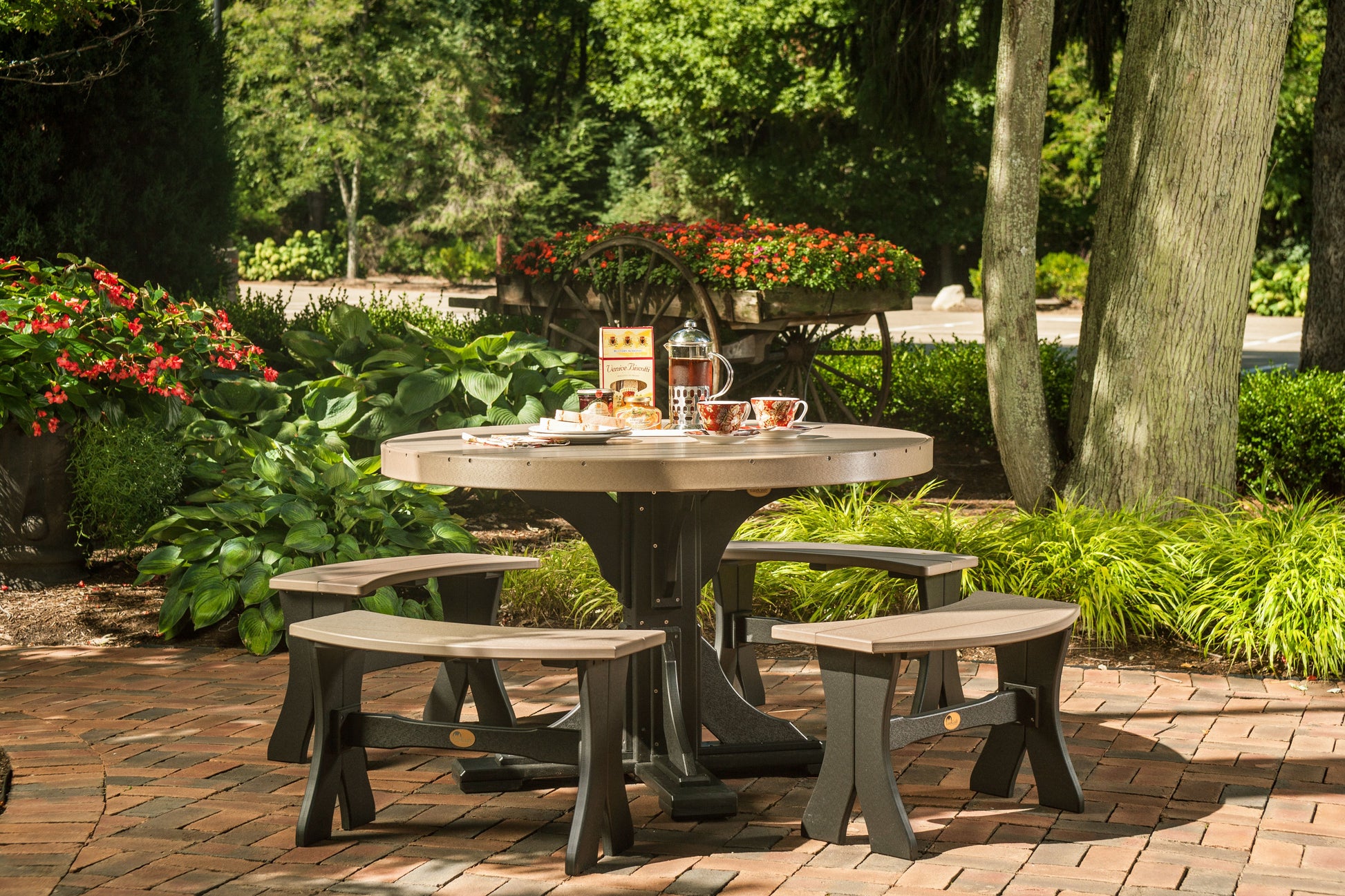 Elegant outdoor setup featuring the Weatherwood & Black 4' Poly Wood Round Dining Table surrounded by a lush garden, ideal for family gatherings and social meals.