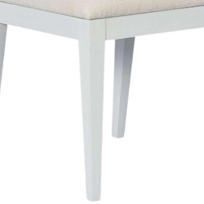 Tapered legs of a white wood dining chair, emphasizing stability and the refined ghost finish for a modern look.