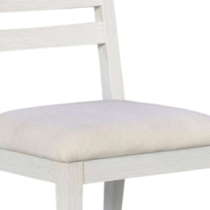 Detailed view of the upholstered seat and sturdy construction of a white wooden dining chair with a warm drift finish.