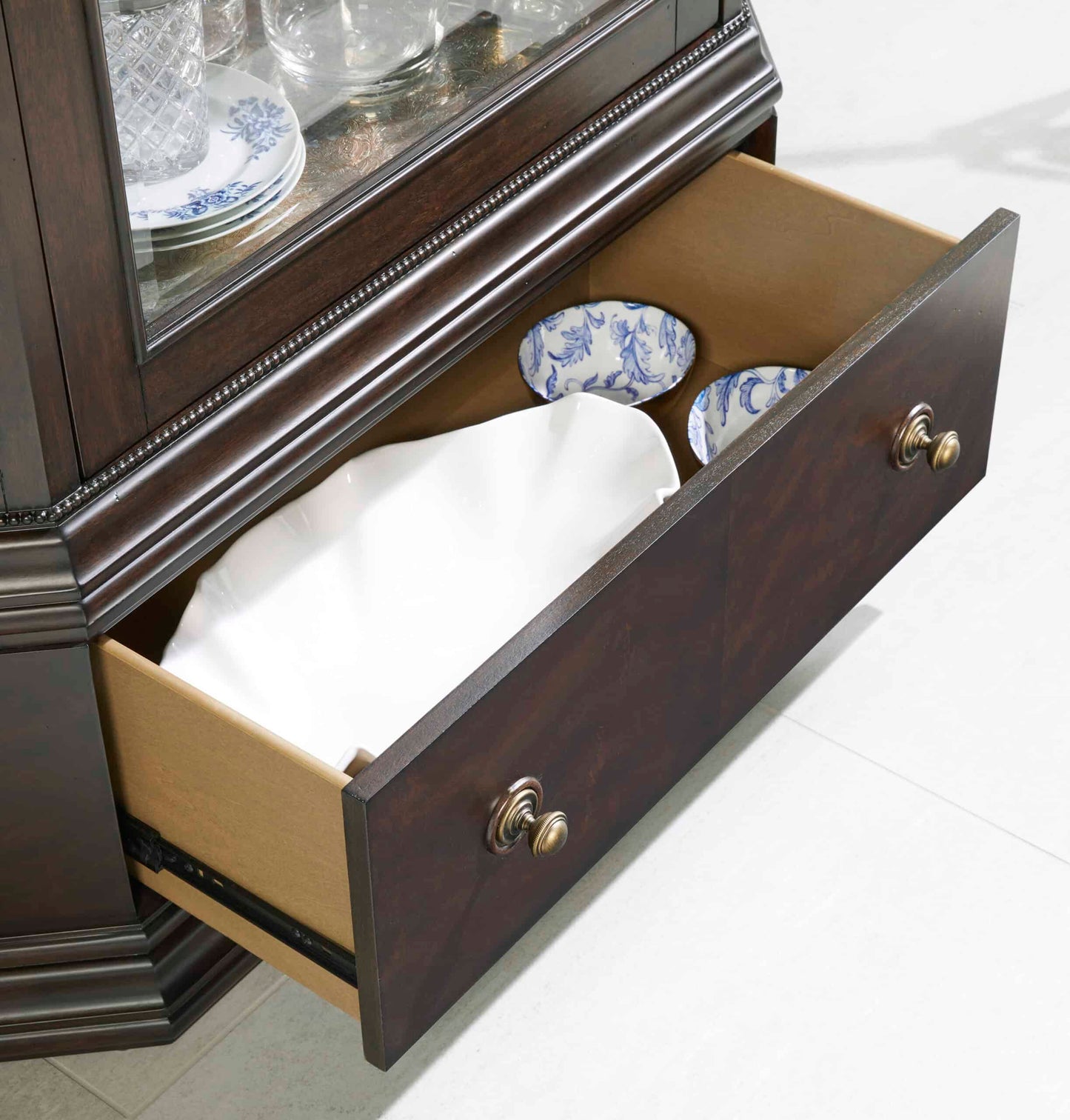 Close-up view of the Revival traditional display cabinet showing the open drawer filled with fine china.