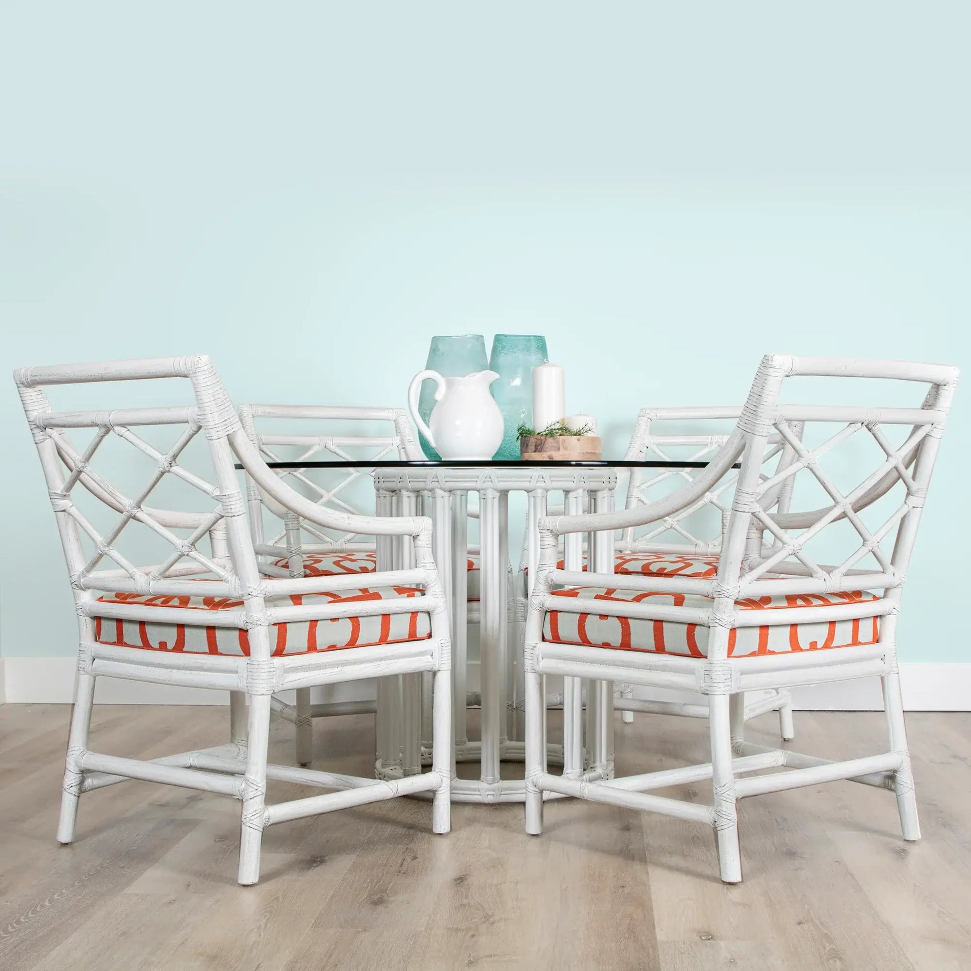 White round metal table base with rattan and glass top, displaying a modern dining setup.