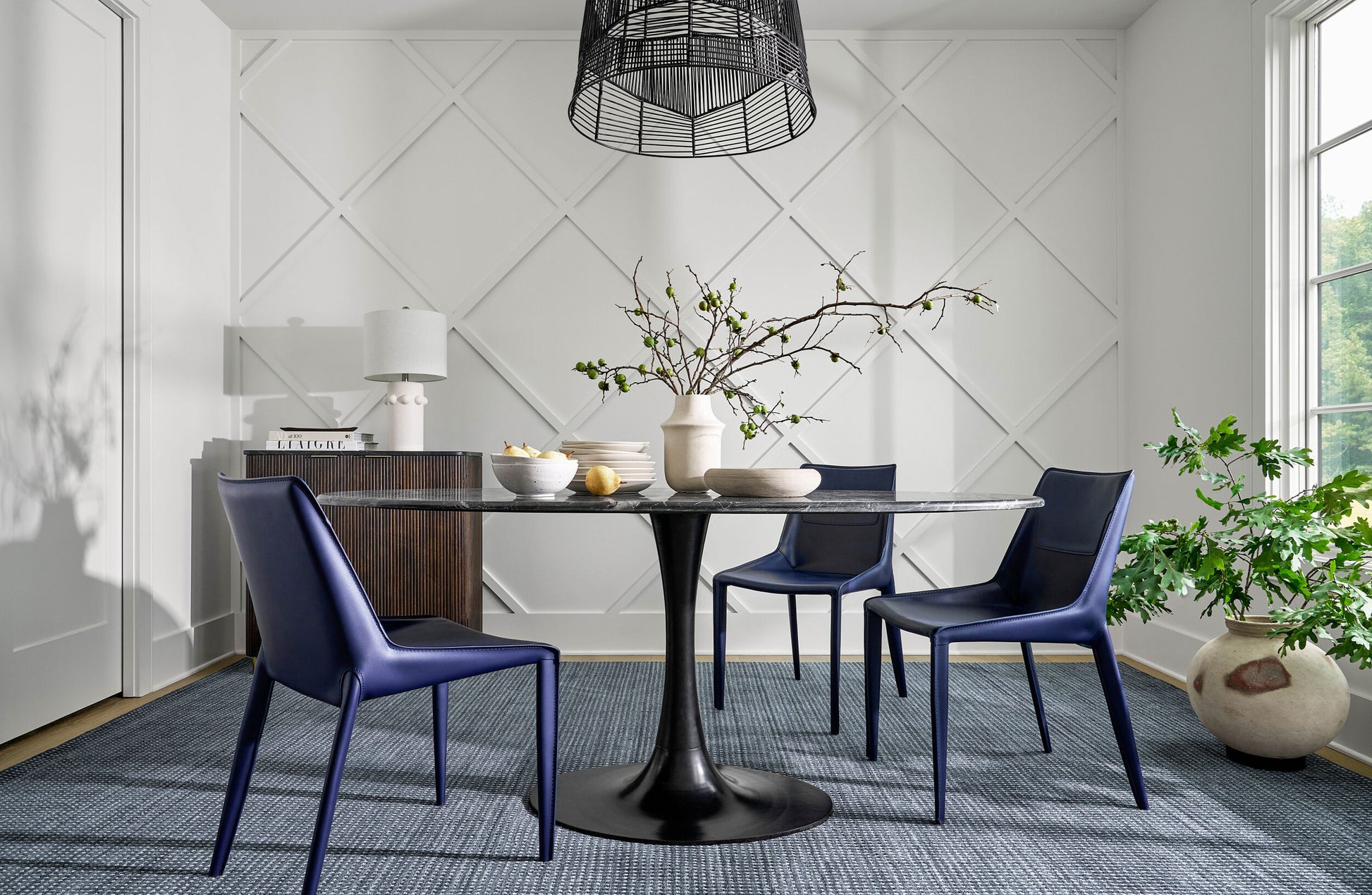 Black marble dining table styled with navy blue chairs in a cozy dining space.