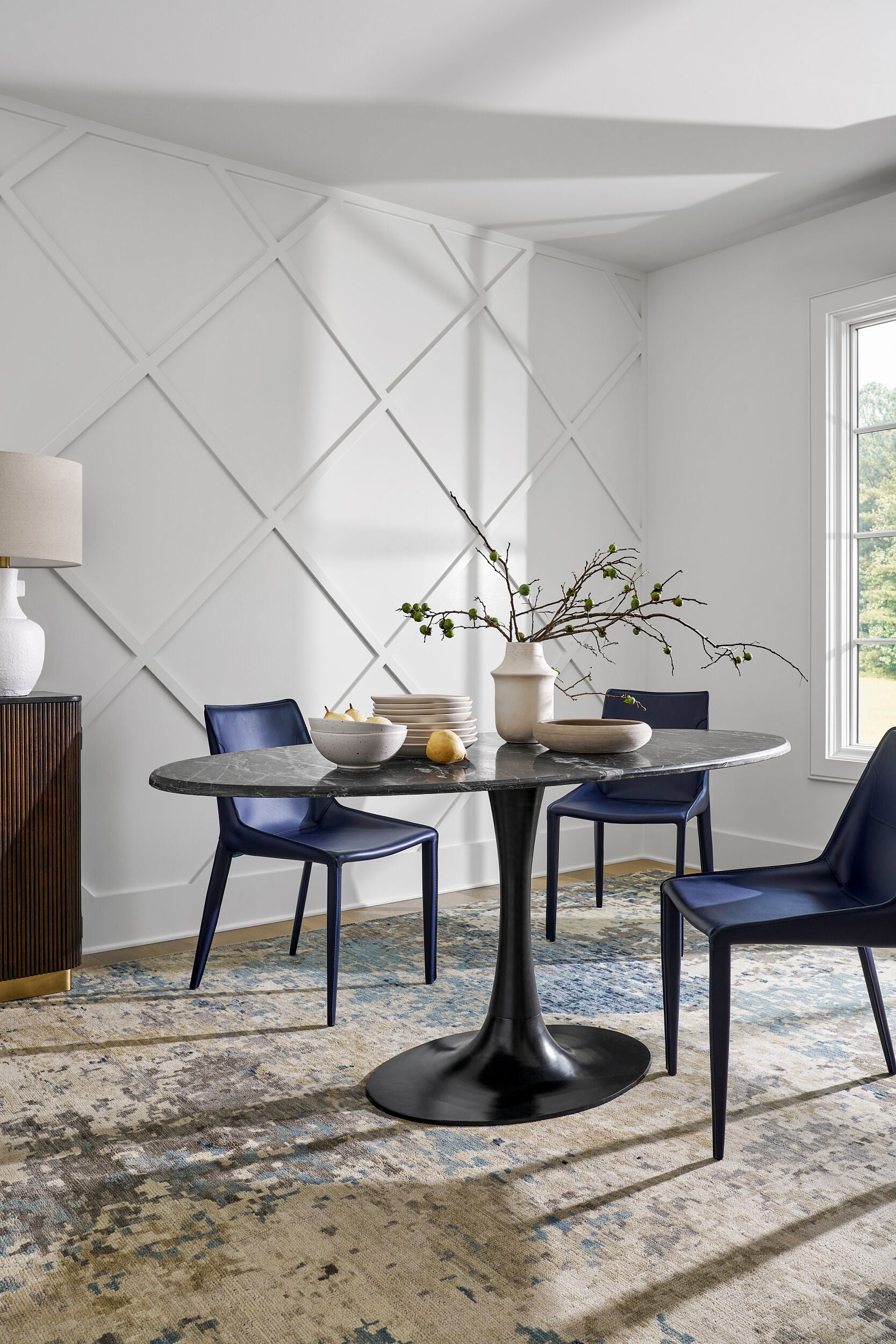 Room scene showcasing the Anatalia black marble dining table against a modern white wall panel backdrop.