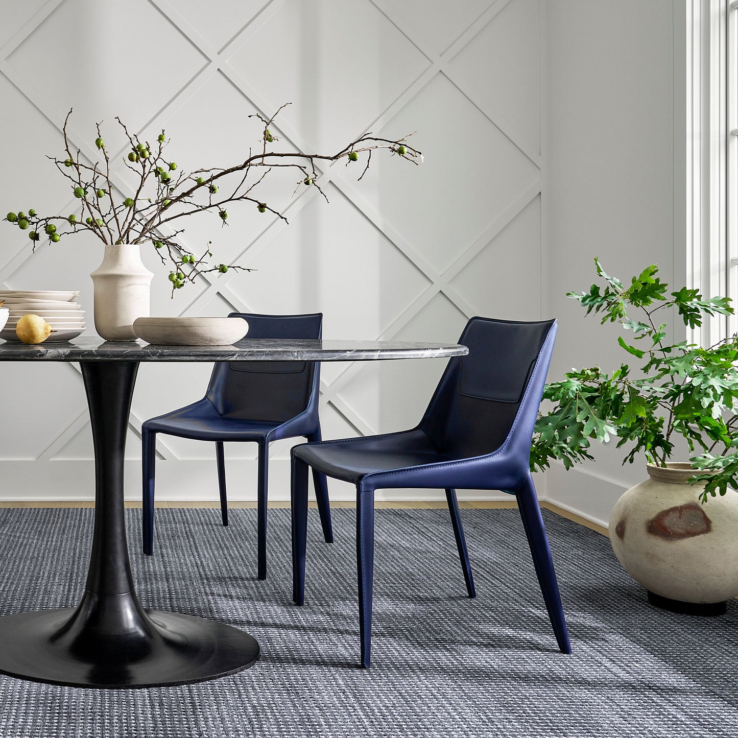 Styled dining room with Anatalia Black Marble Table and two navy blue chairs with decor elements.