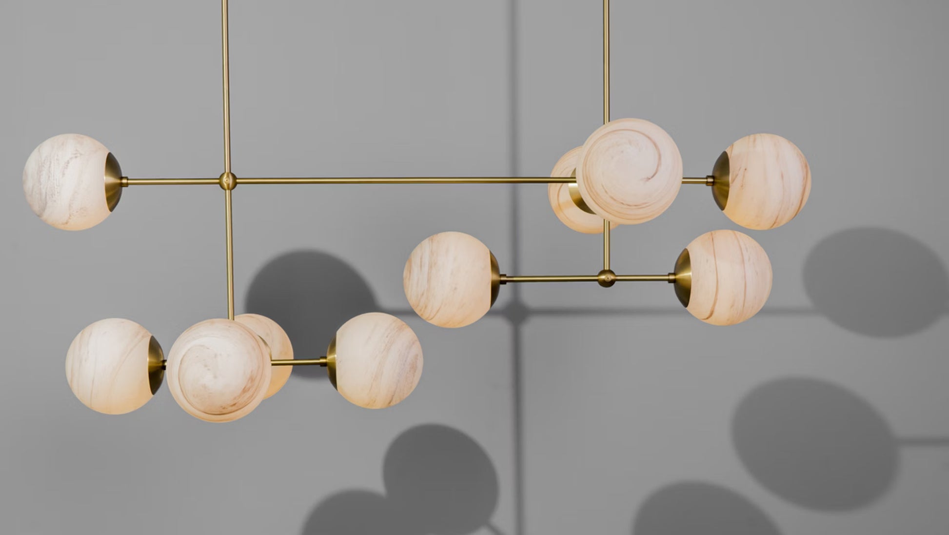 Armstrong Linear Chandelier in burnished brass with marble matte globes, perfect for modern interiors.