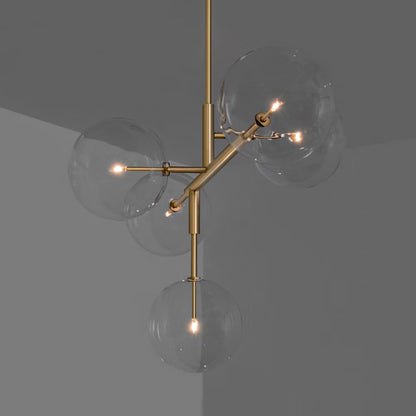 Brass chandelier with five transparent glass globes and asymmetric design.