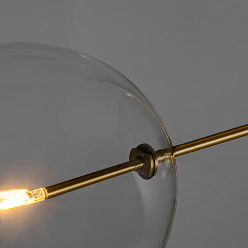 Close-up of borosilicate glass globe with brass arm and LED bulb.