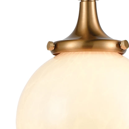 Close-up of the globe-shaped white glass shade with satin brass fixture detailing.