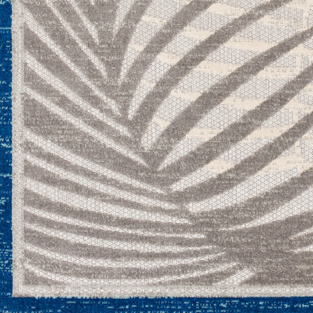 Close-up detail of the grey palm leaf pattern on a blue-bordered rug, showcasing its intricate texture.