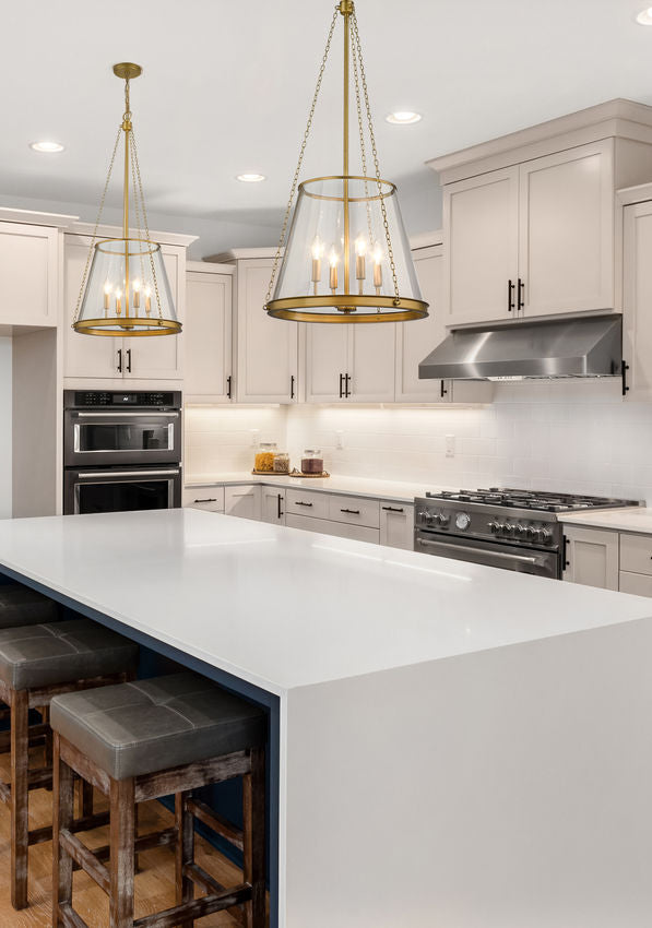 Modern kitchen with two brass cone-shaped glass pendants over white waterfall island.