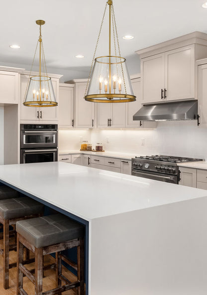Modern kitchen with two brass cone-shaped glass pendants over white waterfall island.